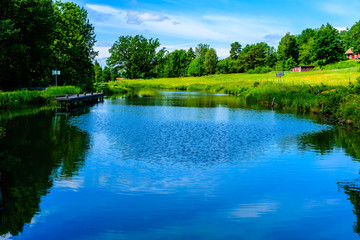Gota canal in Sweden as seen from the locks at Bradtom. The canal with surrounding nature and a pier for temporary mooring at the side.