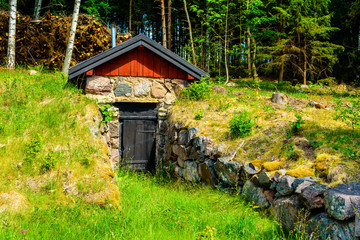 Root cellar close to the forest with stone boulders leading up to the entrance. - 114674934