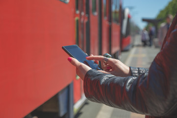 Using cellphone with defocused city tram.