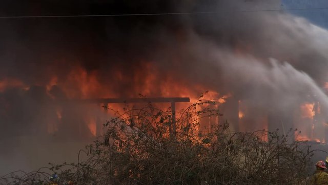 A house fire burns fiercely in spite of powerful streams of water played on it
