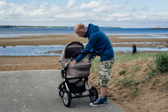 Young Man With Baby Stroller On Beach