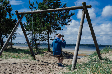 Young man sitting on swing on beach