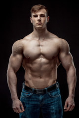 Fototapeta premium Muscular bodybuilder guy doing posing over black background