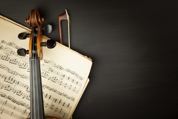 Old violin on dark wooden table. Detail of old violin on a black background. Invitation to the...