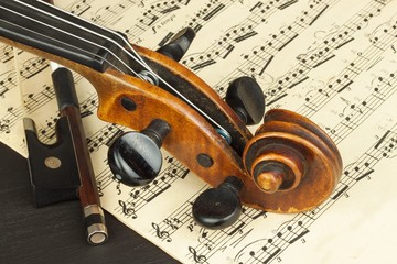 Naklejka premium Old violin on dark wooden table. Detail of old violin on a black background. Invitation to the Violin Concerto.