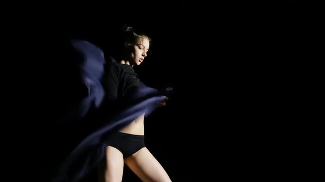 Woman dancing with cloth on black background