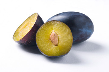 Group of plums with halfs and slices on white background