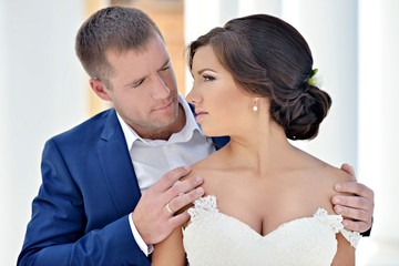 Wedding couple on the nature is hugging each other. Beautiful model girl in white dress. Man in suit. Beauty bride with groom. Female and male portrait. Woman with lace veil. Lady and guy outdoors