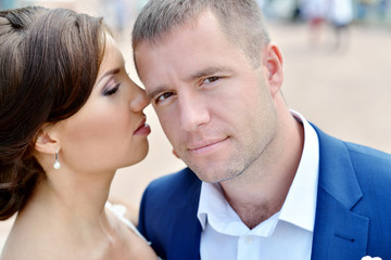 Wedding couple on the nature is hugging each other. Beautiful model girl in white dress. Man in suit. Beauty bride with groom. Female and male portrait. Woman with lace veil. Lady and guy outdoors