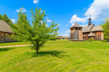 Fototapeta na wymiar Old wooden church on green meadow in Tokarnia village, Poland
