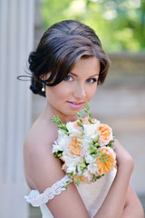 Beauty bride in bridal gown with bouquet and lace veil on the nature. Beautiful model girl in a white wedding dress. Female portrait in the park. Woman with hairstyle. Cute lady outdoors