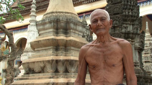 Elderly Cambodian monk standing near temple