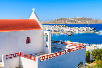 Typical Greek church overlooking Mykonos bay with port, Cyclades islands, Greece