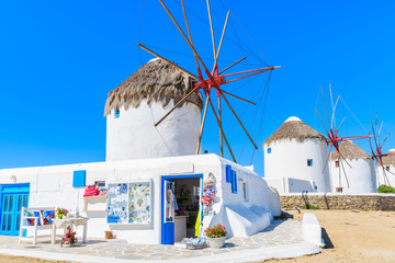 Shop with tourist souvenirs in front of famous traditional windmills on island of Mykonos,...