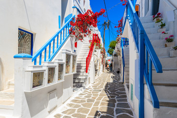 A view of whitewashed street with blue windows and flowers in beautiful Mykonos town, Cyclades...