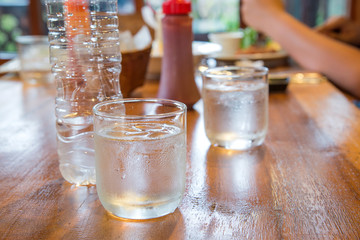 Glass water with ice on wooden table.