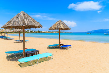 Umbrellas with sunbeds on beautiful sandy Santa Maria beach with turquoise sea water, Paros island, Greece