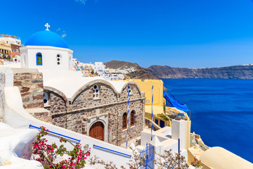 Famous blue dome of a church in Oia village and view of blue sea with caldera on Santorini island, Greece