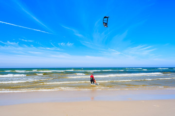 Obraz premium Kitesurfer sailing on blue sea with waves in Bialogora coastal village, Baltic Sea, Poland