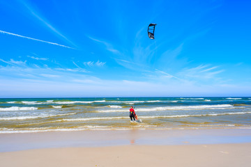 Kitesurfer sailing on blue sea with waves in Bialogora coastal village, Baltic Sea, Poland