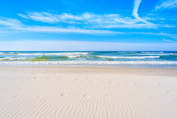 Fototapeta na wymiar A view of white sand beach and waves on blue Baltic Sea, Bialogora coastal village, Poland