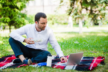 Young and attractive man relaxes in the park at lunch time