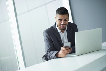 Handsome happy young businessman using mobile phone