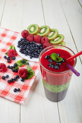 Berry smoothie.Fresh summer cocktail.Blueberry,raspberry,kiwi.Vitamin A. Vitamin C.Checkered napkin.On white wooden table with ingredients.Healthy lifestyle.Diet and weight loss concept.Top view