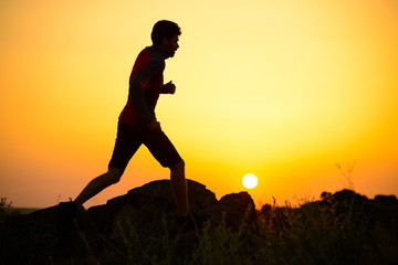 Young Sportsman Running on the Rocky Mountain Trail at Sunset. Active Lifestyle