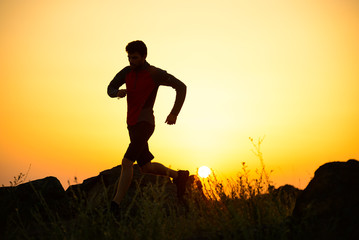 Young Sportsman Running on the Rocky Mountain Trail at Sunset. Active Lifestyle