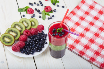 Berry smoothie.Fresh summer cocktail.Blueberry,raspberry,kiwi.Vitamin A. Vitamin C.Checkered napkin.On white wooden table with ingredients.Healthy lifestyle.Diet and weight loss concept.Top view