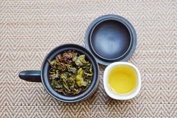 tea cup and leaf in pot on bamboo mat