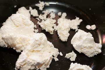 Pieces of cottage cheese on frying pan
