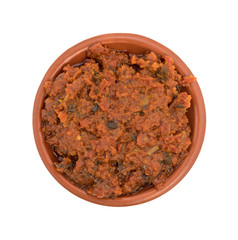 Tomato pesto sauce in a small bowl top view isolated on a white background.