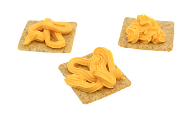 Canned cheese on organic whole grain wheat crackers isolated on a white background.