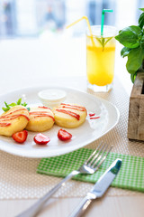 Cheese cookies with strawberry sauce, mint leaves on white plate and glass of lemon cold drink in restaurant.