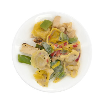 Chicken and tortellini TV dinner on a white plate isolated on a white background top view.