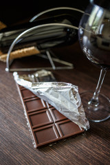 A chocolate bar in foil with glass of red wine