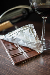 A chocolate bar in foil with glass of red wine