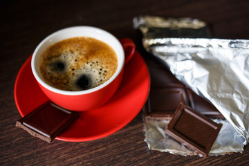 Cup of strong coffee with chocolate bar in foil