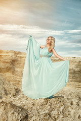 Fototapeta na wymiar Girl in the blue dress in the sand