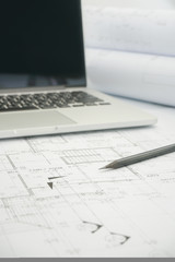 black pencil and computer laptop on architectural drawing paper for construction