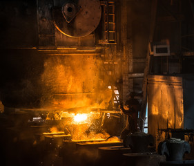 Obraz na płótnie Canvas Steelworker pours liquid metal into molds from tank 