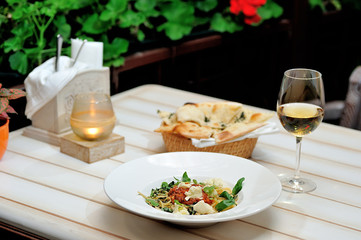 The image is very tasty spaghetti bolognese with cheese and basil on a white table.