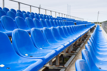 Empty plastic blue chairs at stadium in a row