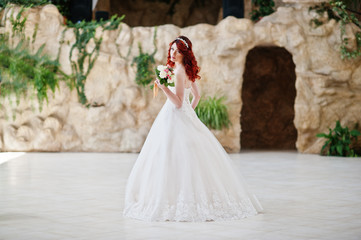 Obraz premium Charming red-haired bride with wedding bouquet at hand posed at
