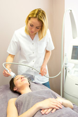 Fototapeta premium Young attractive blond beautician woman doing a facial massage t