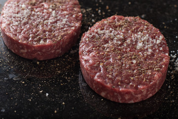 Meat for burgers, grilling, barbecue, bbq. Fresh, spicy, uncooked, delicious beef for hamburgers on dark background with copy space closeup
