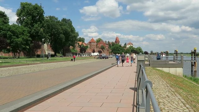 TANGERMUENDE, SAXONY-ANHALT/ GERMANY June 29 2016: historical brick stone town wall of Tangermuende directly on Elbe river. People walking along and cars parking.