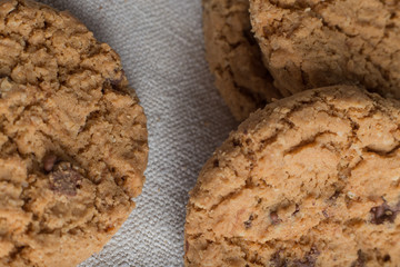 Cookies pile with chocolate chip on light textile background. Delicious morning snacks for breakfast, brunch and lunch. Appetizing, healthy, sweet, scrummy, and fast food.